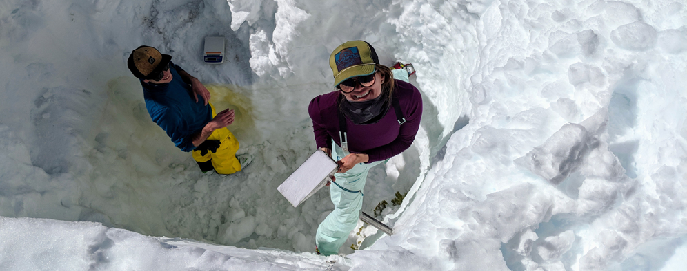 2 researchers with equipment in deep snow pit